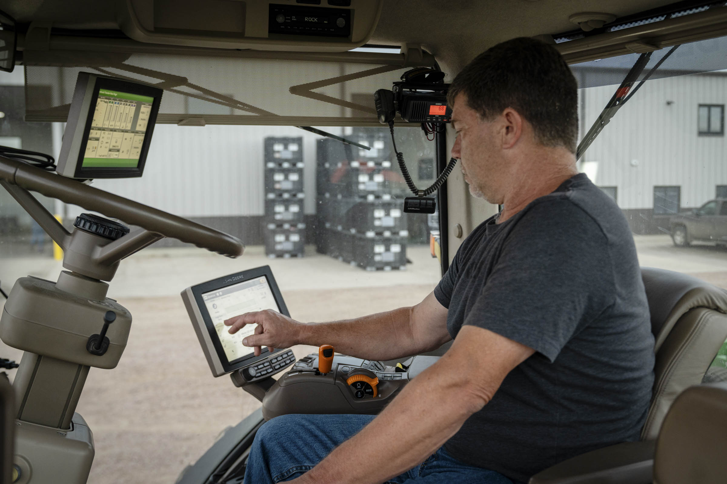 Man using computer on farm equipment.