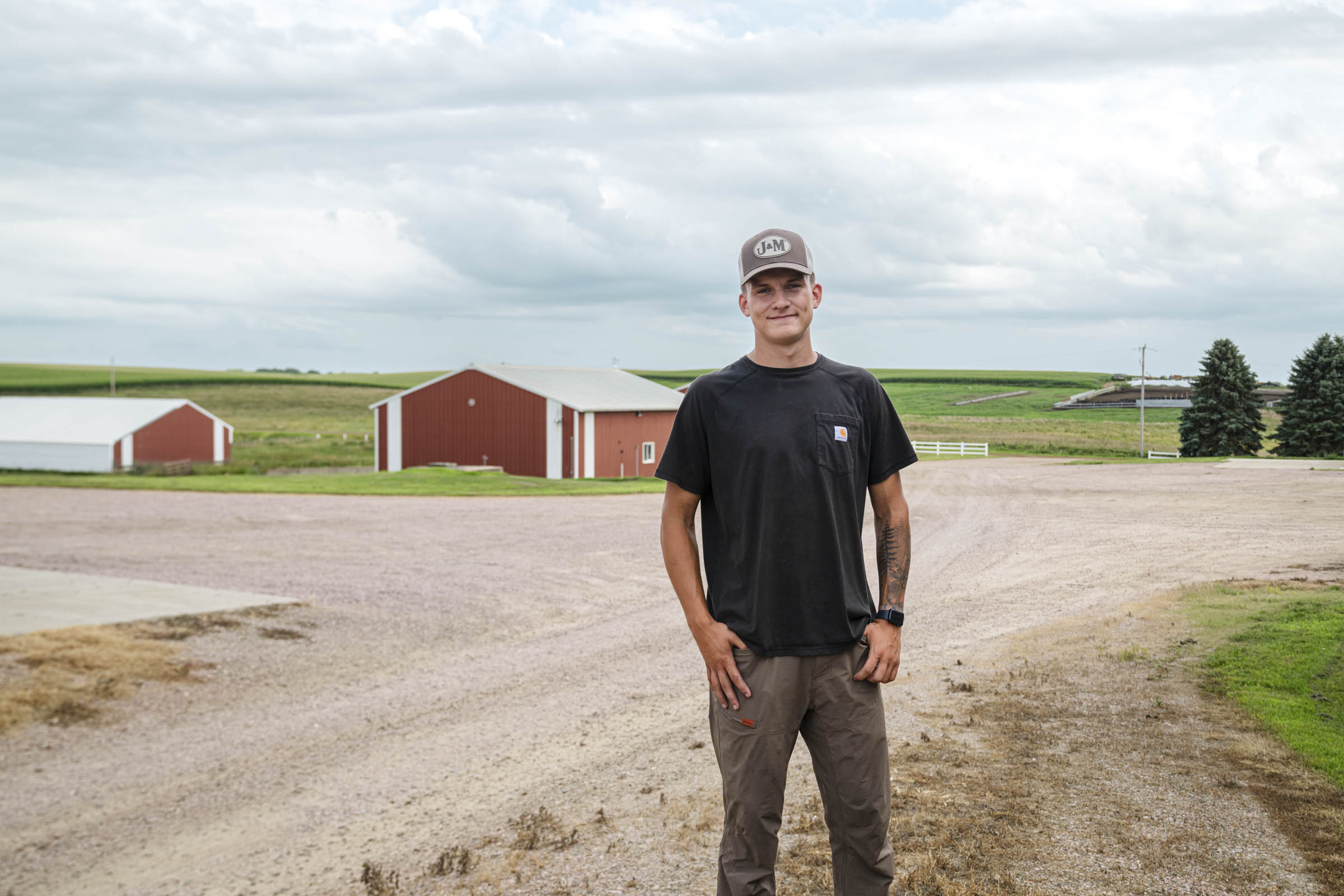 Man standing in a dirt road in front of barns.