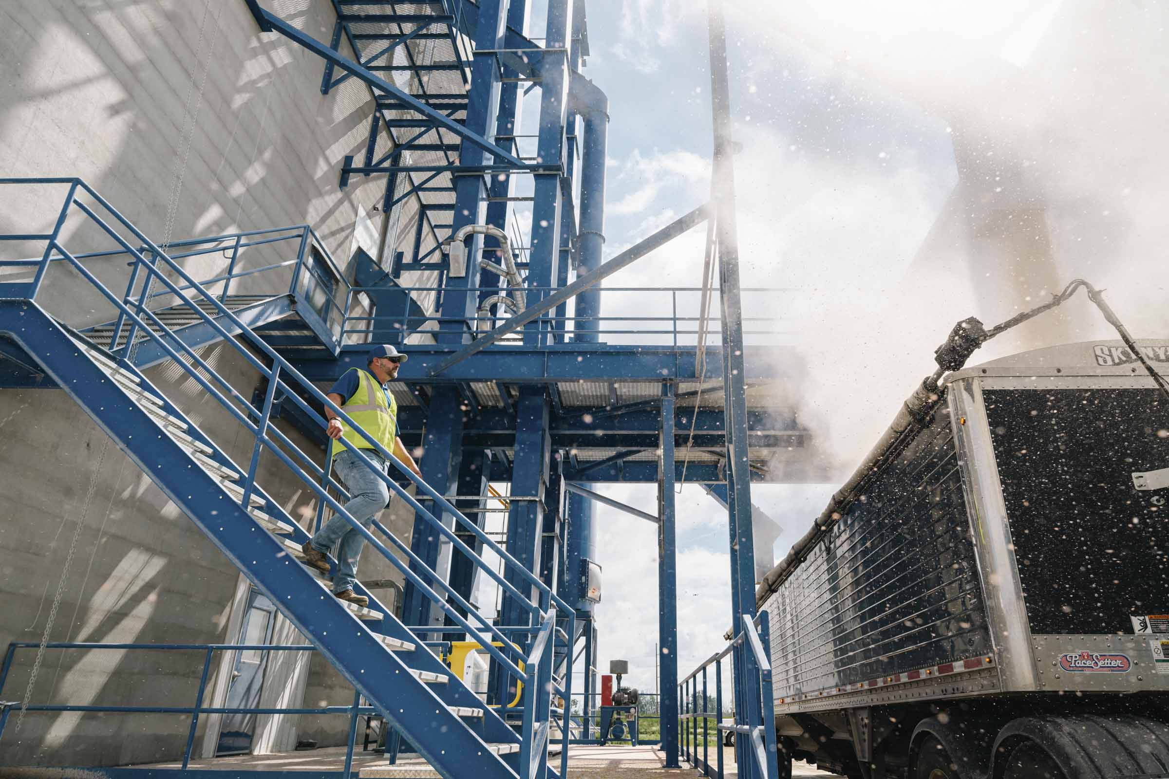 Man in hardhat standing outside manufacturing facility.