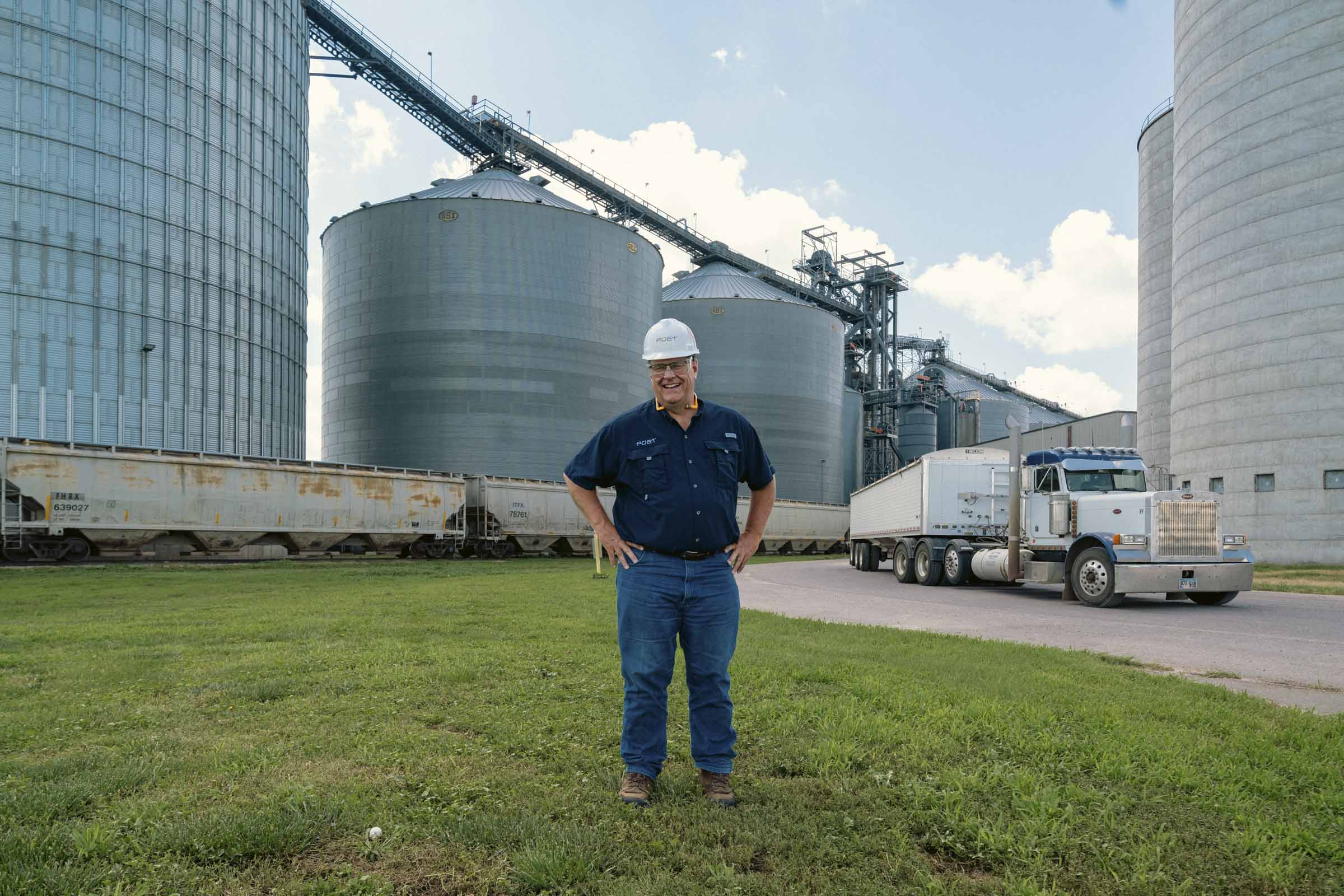 Man in hardhat standing outside manufacturing facility.