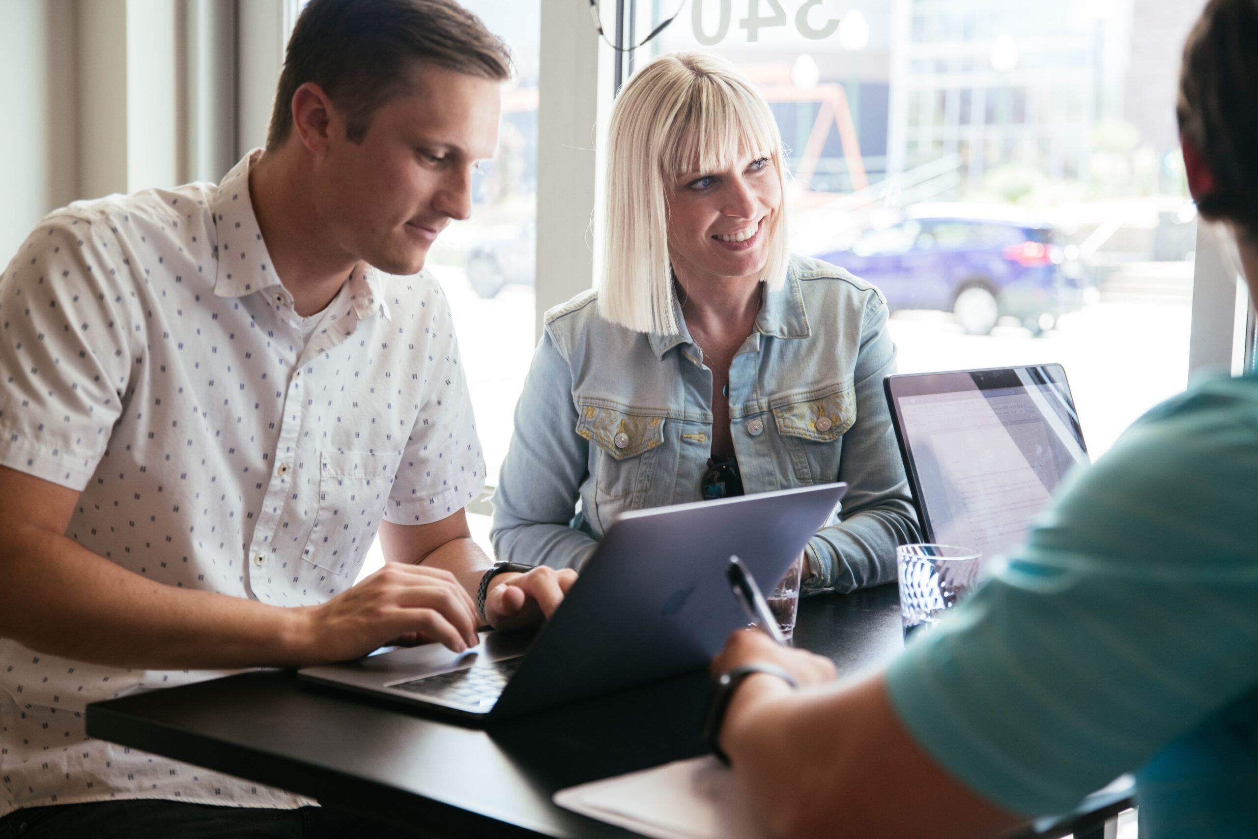 Four people sitting at a table with laptops.